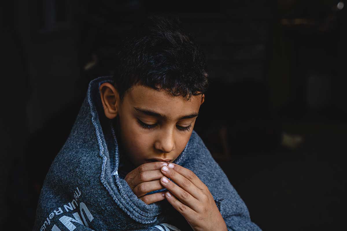 A young boy wrapped in a UNHCR blanket